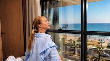 Eine Person sitzt am Fenster mit Blick auf den Strand.