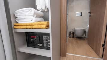 A bathroom with a toilet, a trash bin, and a towel rack with white and yellow towels.