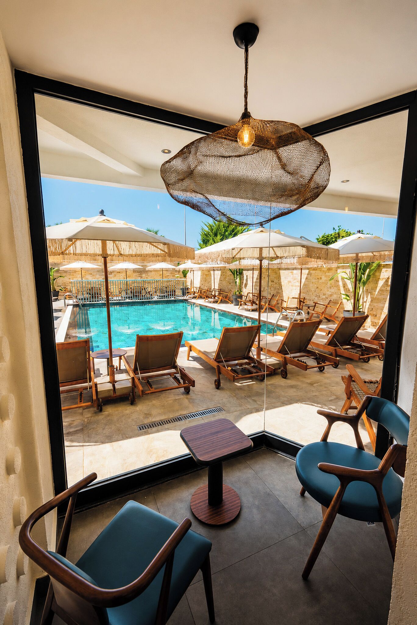 A poolside area with lounge chairs, umbrellas, and a view of the pool.