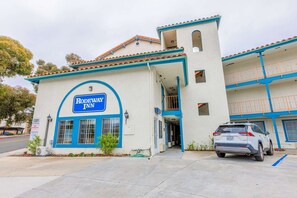 Um edifício de dois andares com uma placa indicando 'Rodeway Inn' e um carro branco estacionado na frente.