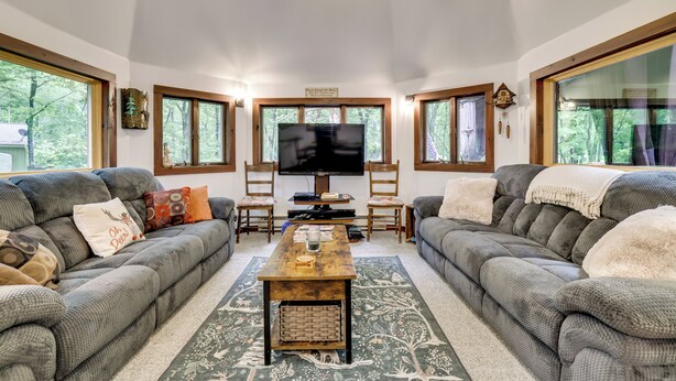 A living room with two grey sofas, a wooden coffee table, a TV, and large windows with a view of trees. - Game Room, Deck & Fire Pit! Pocono Mtn House (Blakeslee)