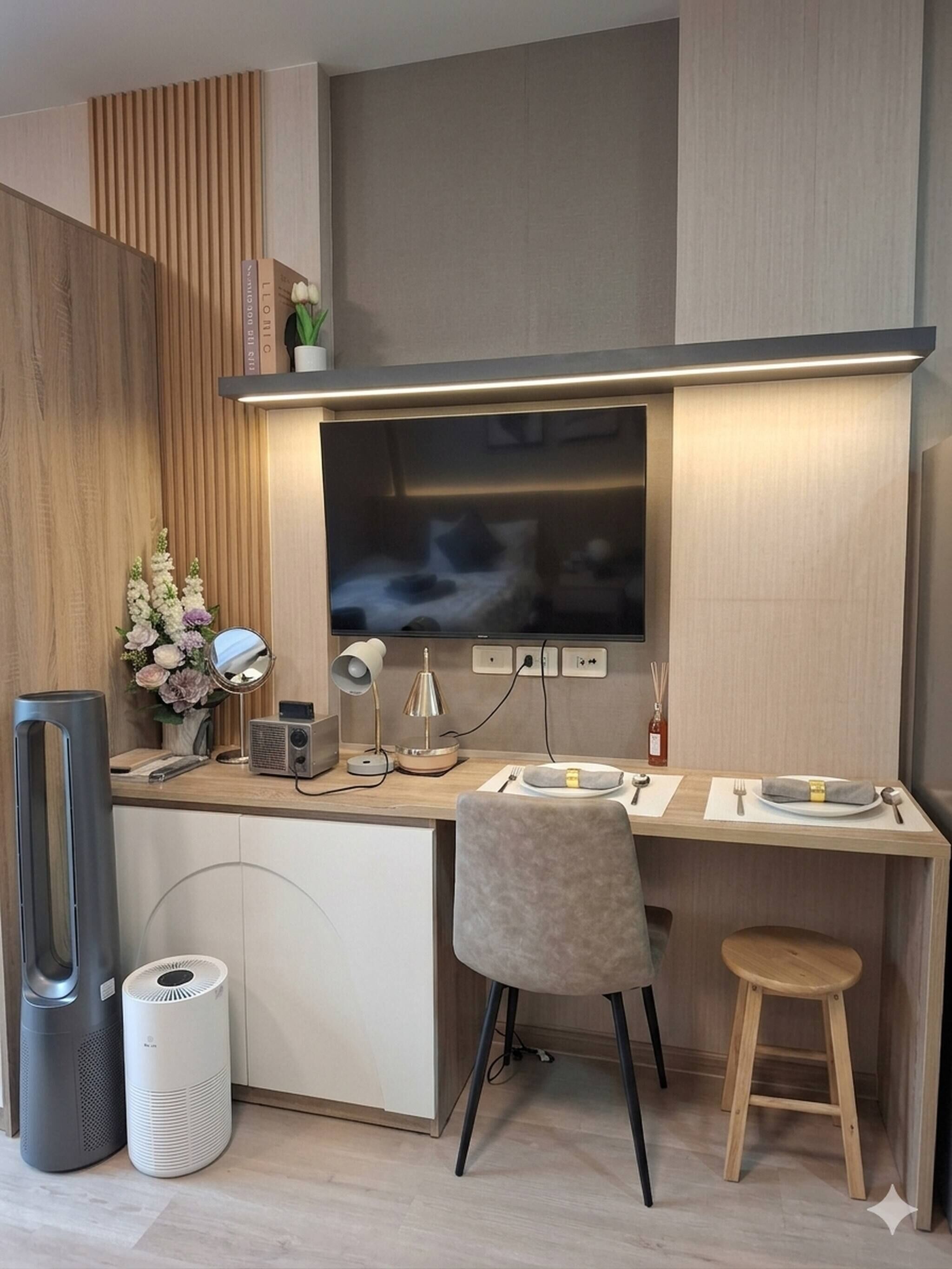 A modern kitchen with a flat-screen TV, a dining area with a chair and stool, and a built-in stove.