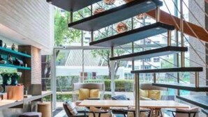 A modern interior with a glass wall, a dining area with a table and chairs, and shelves with decorative items. - Modern Studio Pool View, King bed, BTS Punnawithi (Bangkok)