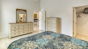 Une chambre à coucher avec un lit, une commode, un miroir et un ventilateur de plafond.