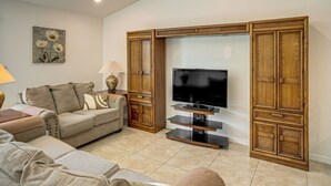 Un salon avec un canapé, un meuble pour la télévision et des armoires en bois.