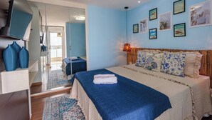 Ein Schlafzimmer mit einem Bett, einem Kleiderschrank, einem Spiegel und einer Wand mit gerahmten Bildern.