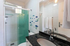 A bathroom with a glass shower enclosure, a black sink, and a mirror with a towel rack.