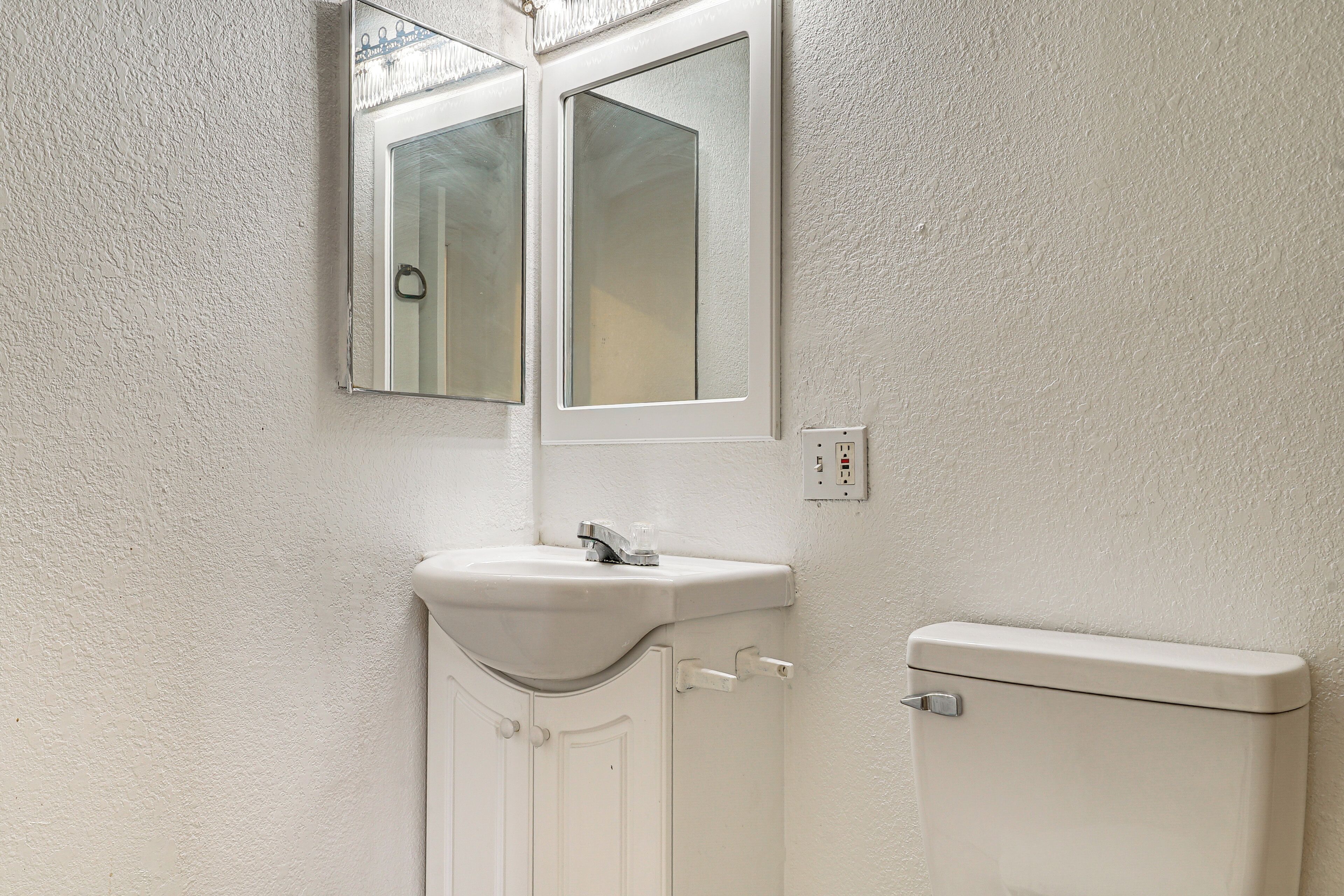 A bathroom with a white sink, a mirror, and a toilet.