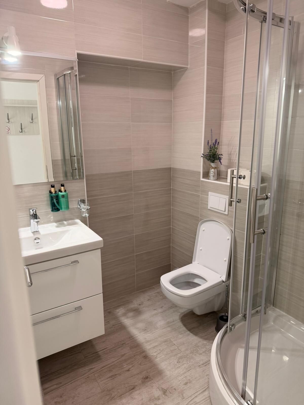 A modern bathroom with a sink, toilet, and glass shower enclosure.