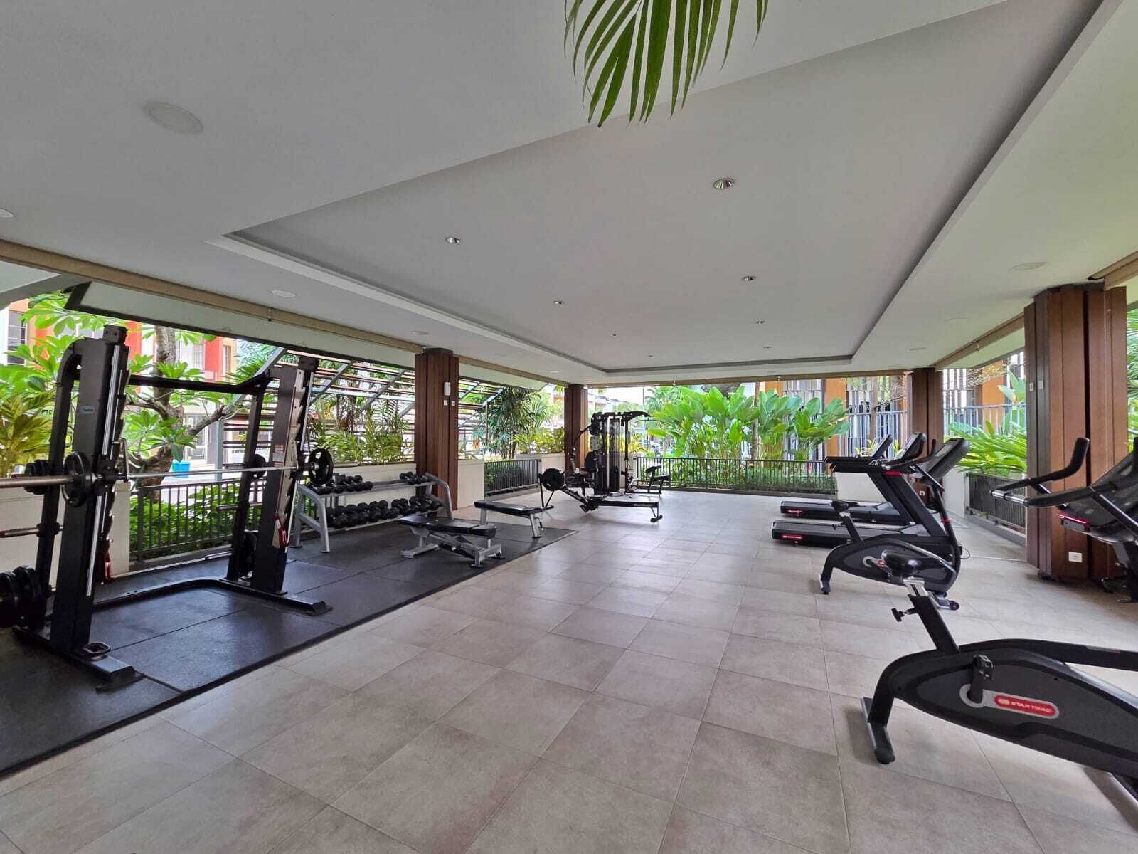 A gym with treadmills, weight machines, and dumbbells.
