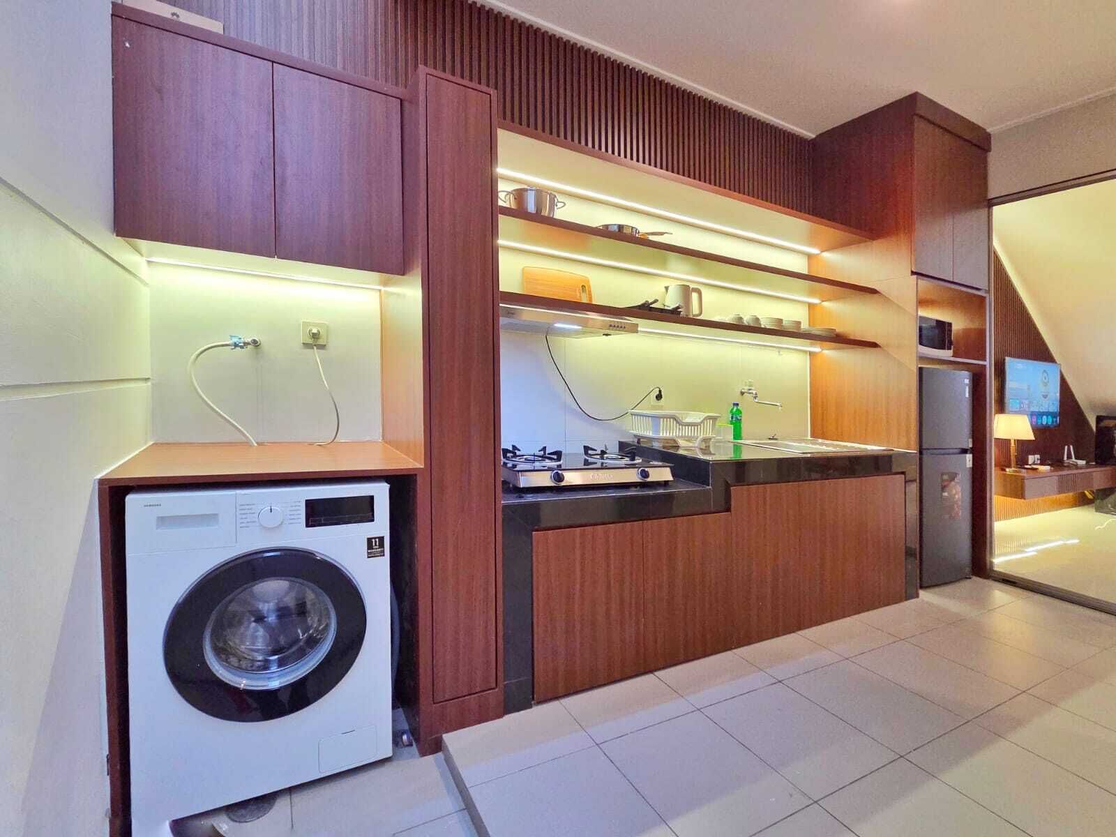 Une cuisine moderne dotée d’appareils électroménagers intégrés, de meubles de rangement en bois et d’un lave-linge.