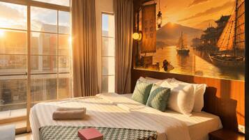 A hotel room with a large bed, a view of a cityscape through the window, and a painting of a river scene on the wall.