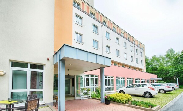 Hotellissa on katettu sisäänkäynti, ulkotila istumiseen ja pysäköintialue.