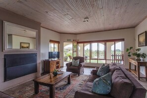 Ein geräumiges Wohnzimmer mit einer großen Couch, einem Couchtisch, einem Fernseher und einem Kamin.