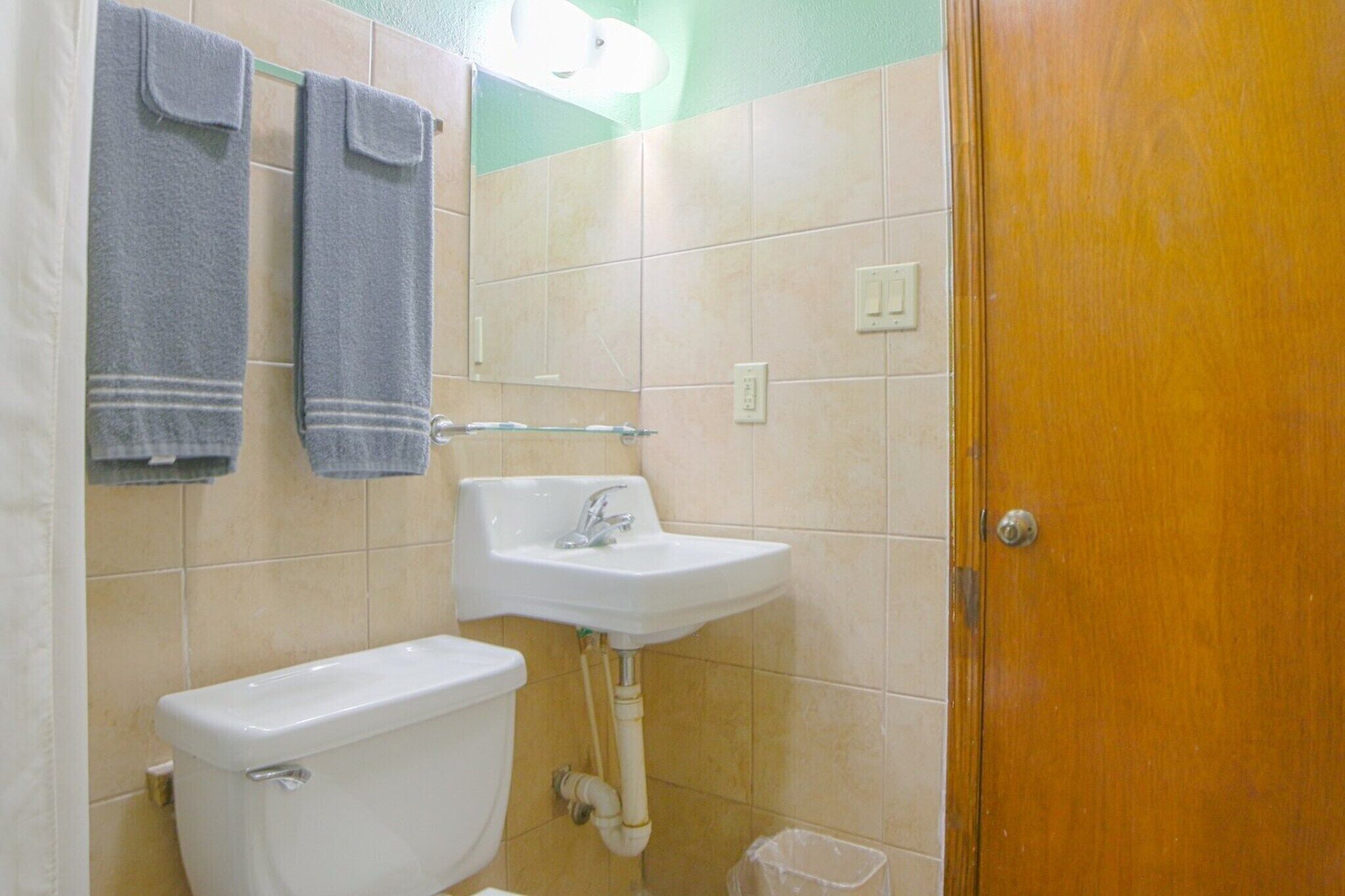 A bathroom with a toilet, sink, and two towels hanging on the wall.