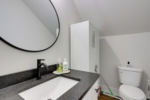 Une salle de bain avec un lavabo blanc, un robinet noir et des toilettes.