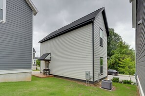 Un immeuble résidentiel doté d’un patio couvert, d’une voiture garée dans l’allée et d’une pelouse.