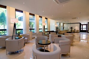 Eine großzügige Lobby mit modernen Möbeln, großen Fenstern und einem Klavier.