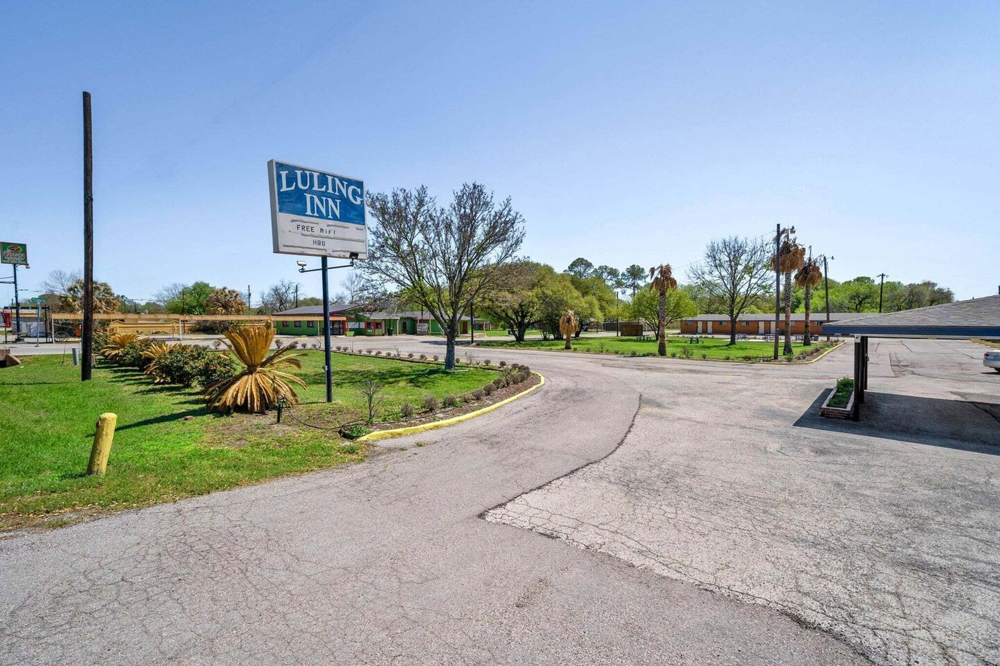 Señal del Luling Inn, un estacionamiento y un área con césped y árboles.