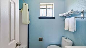 A bathroom with a toilet, a sink, a window, and a towel rack.