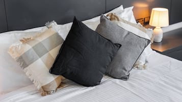 Un lit avec des oreillers, une lampe de chevet et une tête de lit sombre.