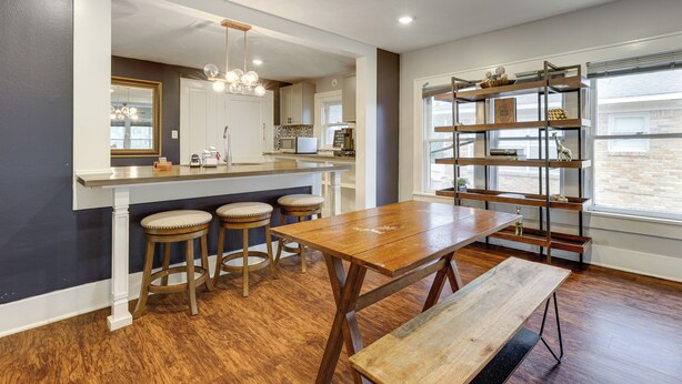Una cocina moderna con una isla de madera, taburetes de bar y una estantería empotrada.