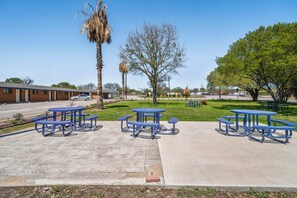 A parking lot with picnic tables and a building in the background.