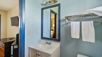 A bathroom with a sink, mirror, towel rack, and toilet.