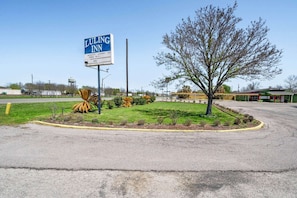 A Luling Inn sign, a parking lot, and a landscaped area with a tree and shrubs.
