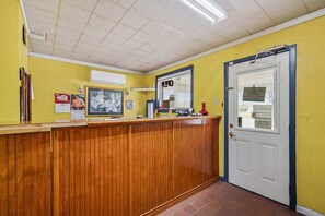 A reception area with a wooden counter, a door, and a bulletin board with notices.