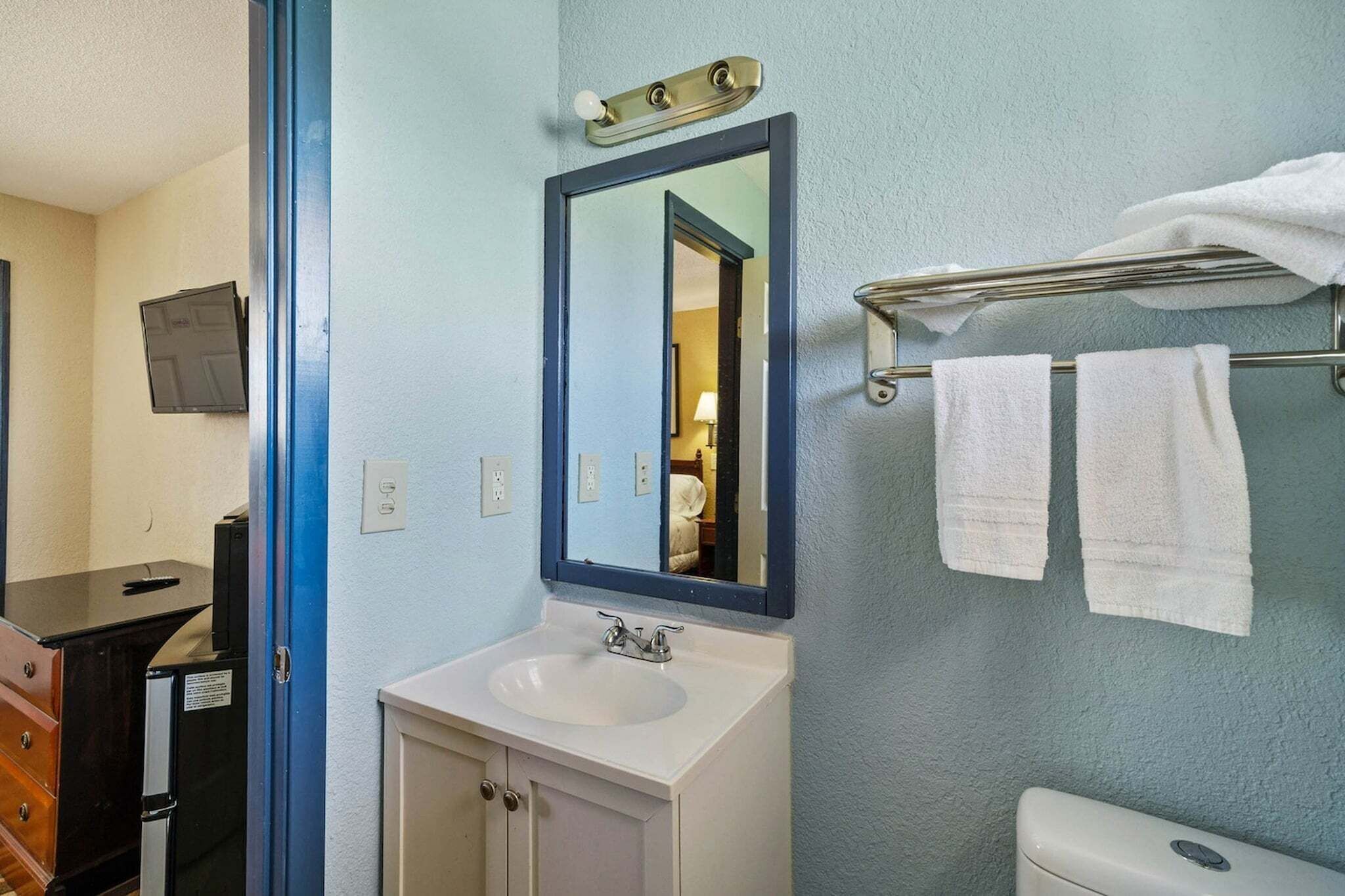Un baño con lavabo, espejo, toallero y retrete.