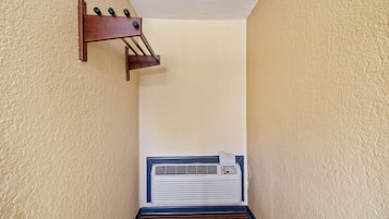 A narrow hallway with a wall-mounted air conditioning unit and a wooden rack with bottles.