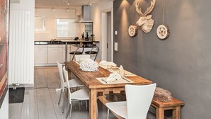 Eine moderne Küche mit weißen Schränken, einem Holztisch und Stühlen.