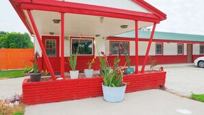A building with a red and white exterior, a covered porch, and potted plants.