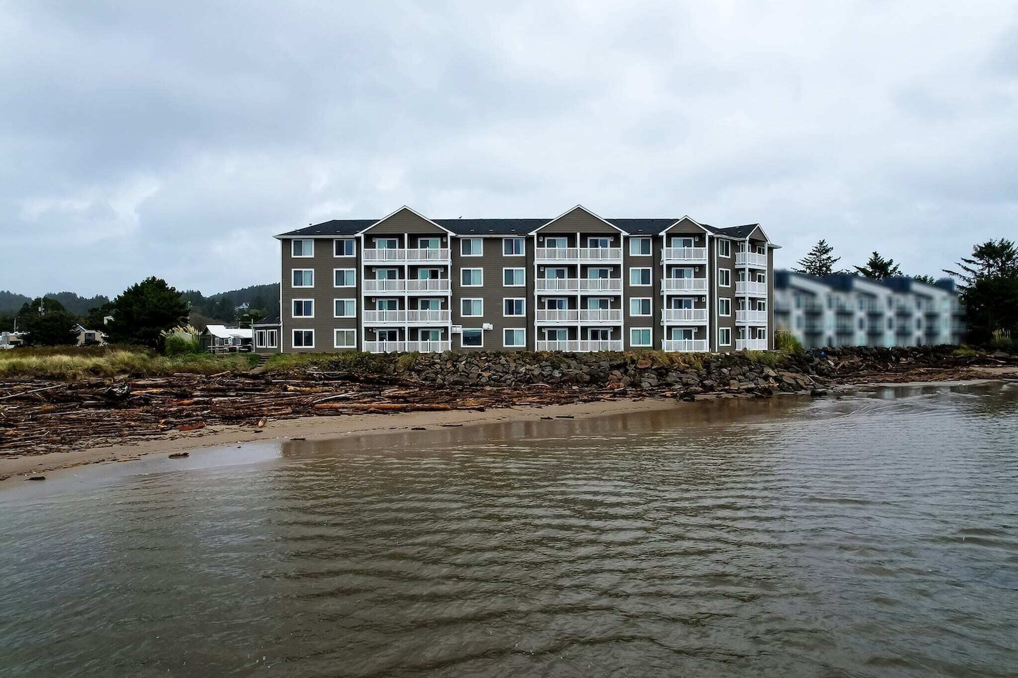 A multi-story hotel with balconies, located near a body of water.