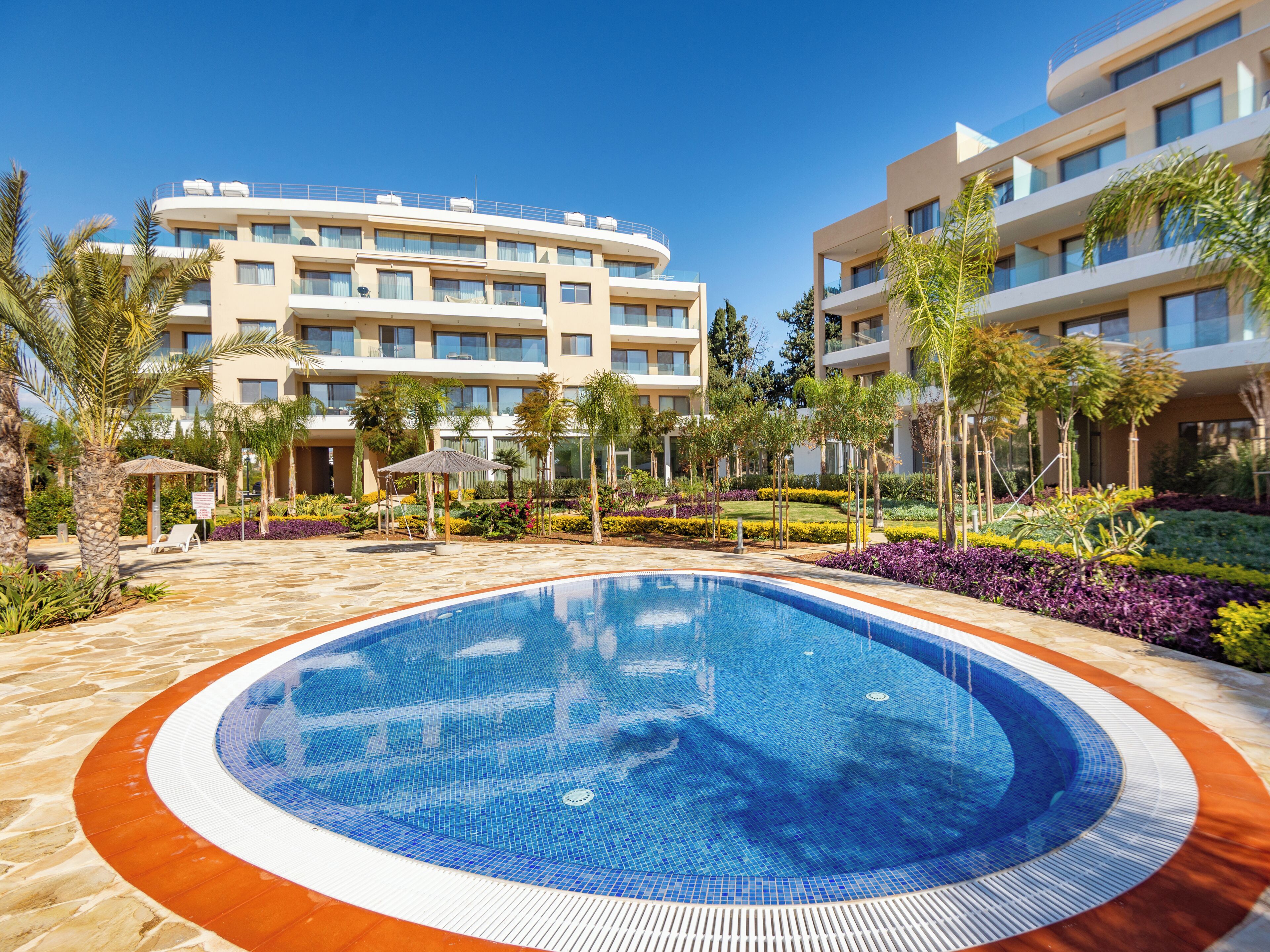 Un hôtel doté d’une piscine entourée de palmiers et d’un jardin bien entretenu.