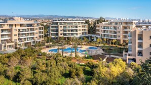 Un complexe d’appartements moderne composé de plusieurs immeubles, doté d’une piscine centrale et entouré de verdure.
