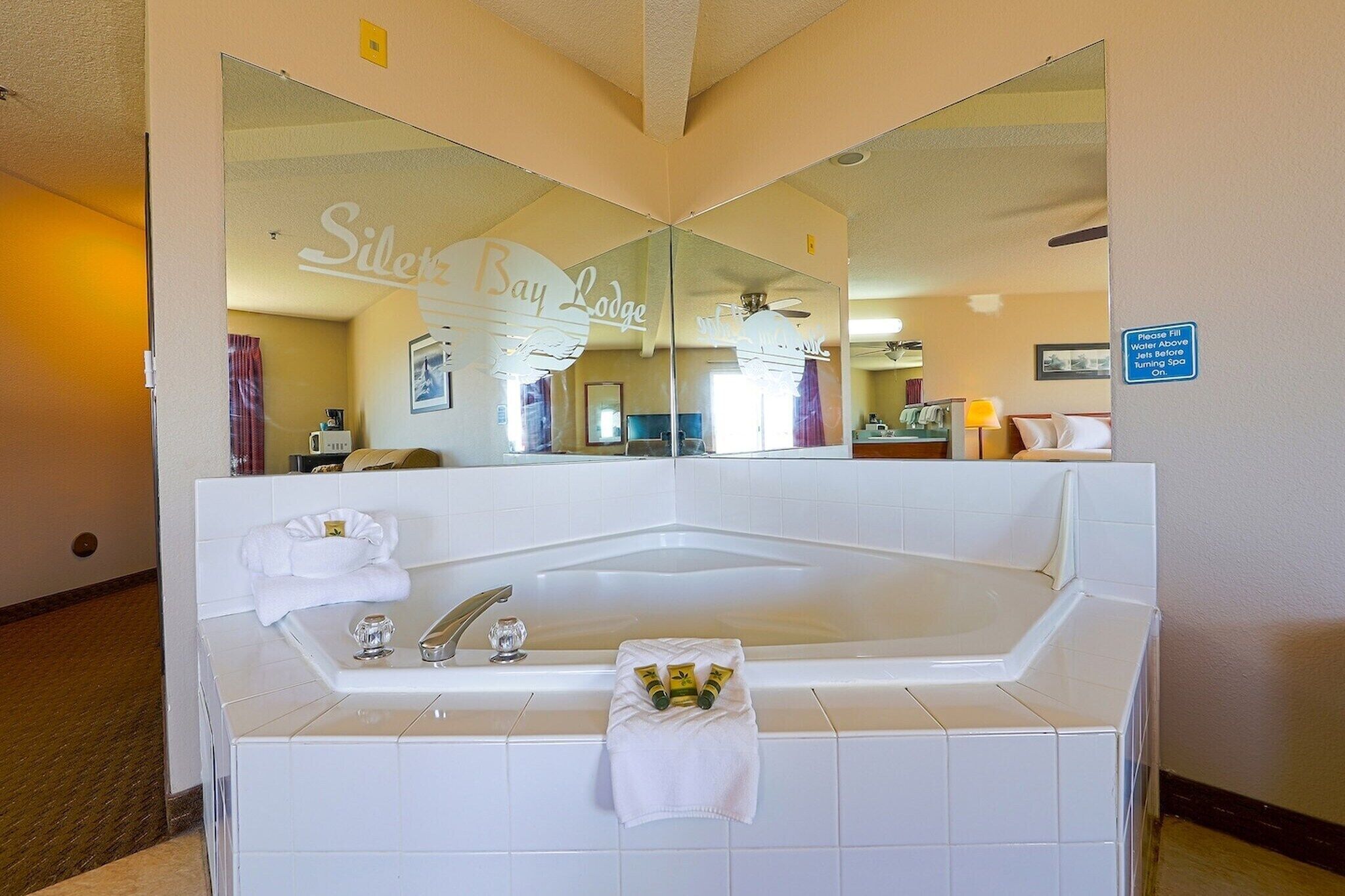A hotel bathroom with a large mirror, a bathtub, and a towel rack.