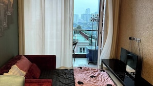 Ein Zimmer mit Bett, Fernseher, Sofa und Fenster mit Blick auf die Stadt.