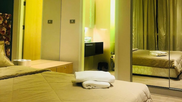 Ein Hotelzimmer mit einem großen Bett, einem Spiegel, einem Badezimmer mit Toilette und Waschbecken.