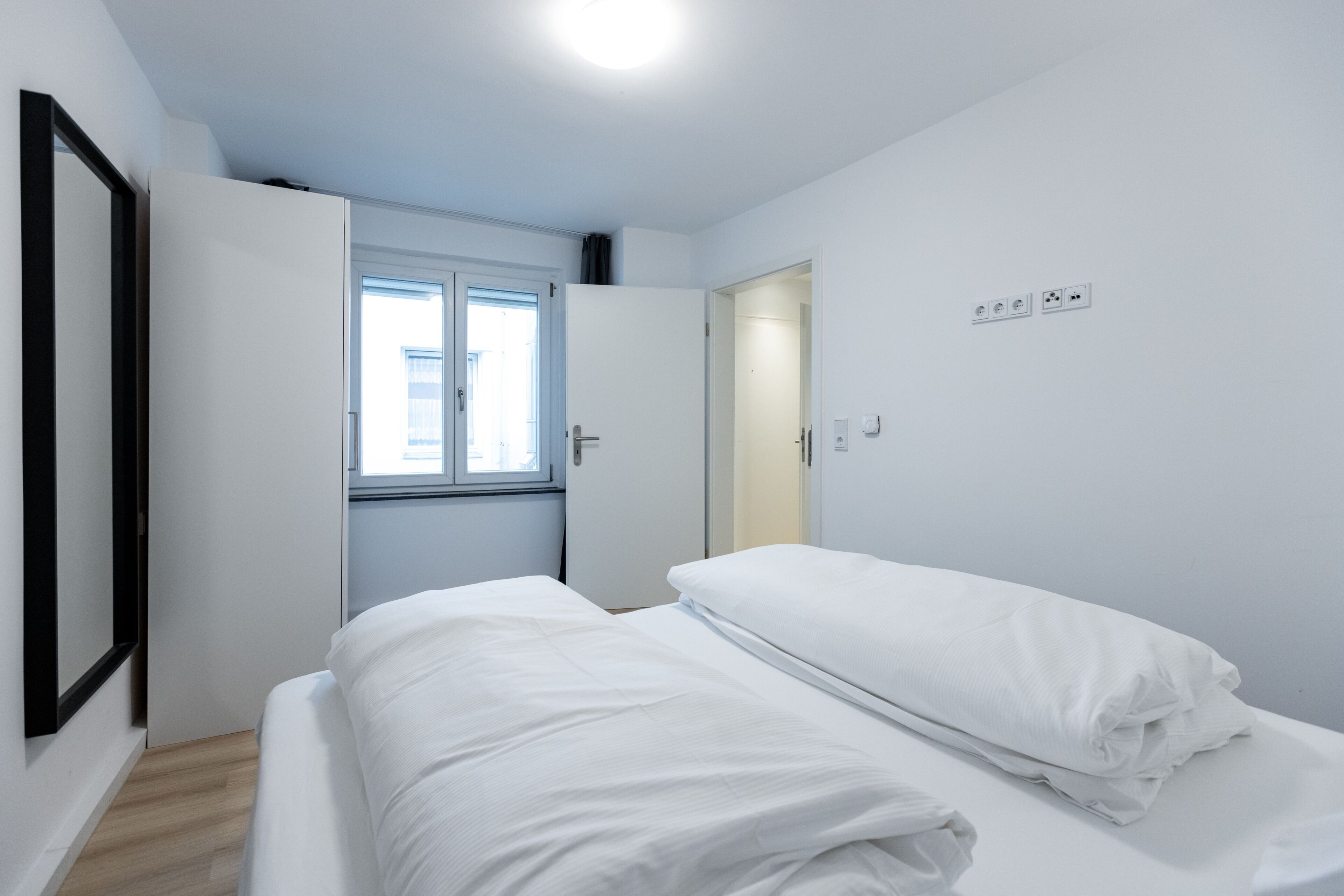 Ein Schlafzimmer mit Bett, Fenster und Tür.