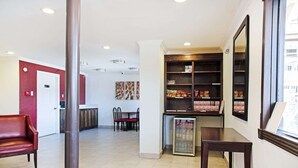 A hotel lobby with a reception desk, seating area, and a refrigerator stocked with beverages. - Premium King Bed Accessible (McAllen TX)