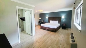 A hotel room with a bed, bedside lamps, a desk, and a window. - Premium King Bed Accessible (McAllen TX)
