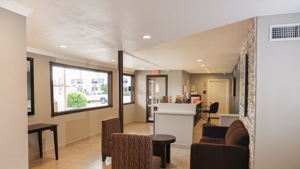 A lobby with seating, a reception desk, and large windows.