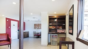 A hotel lobby with a reception desk, seating area, and a refrigerator stocked with beverages.