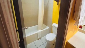 A bathroom with a bathtub, toilet, and shower curtain. - 2 Full Beds Non-Smoking (Sulphur LA)