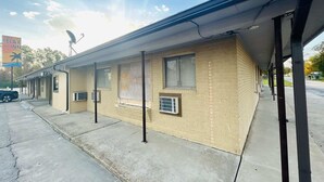 A motel with a brick facade, air conditioning units, and a covered parking area. - 2 Full Beds Non-Smoking (Sulphur LA)