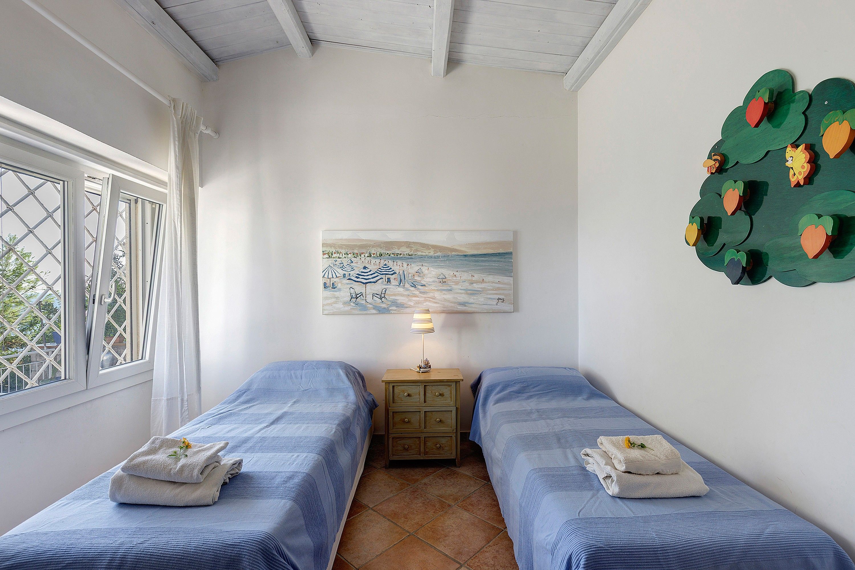 Una stanza con due letti, un quadro, una lampada e un elemento decorativo a parete.