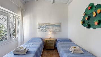 Una stanza con due letti, un quadro, una lampada e un elemento decorativo a parete.