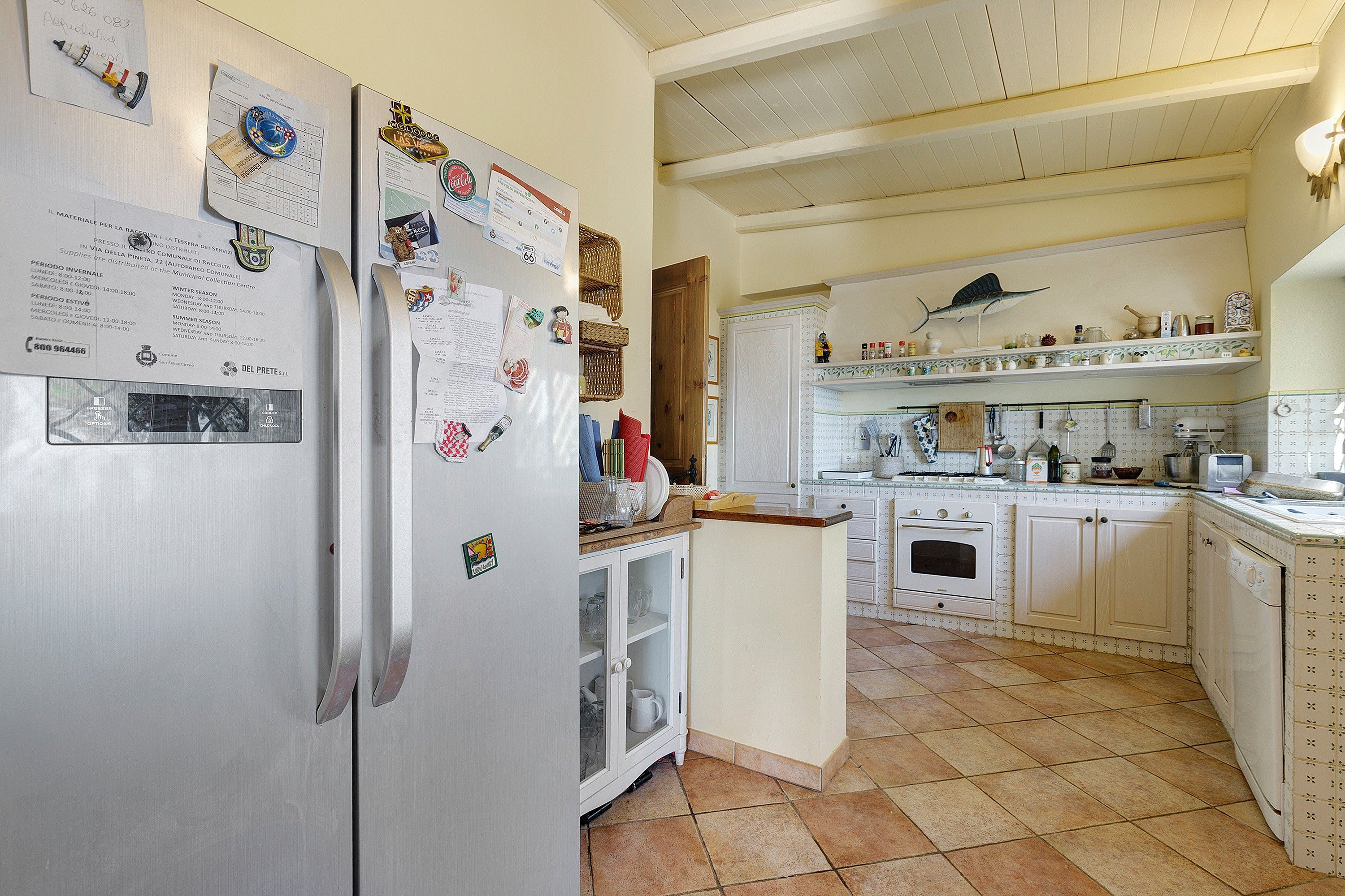 A kitchen with white cabinets, a stainless steel refrigerator, and a tiled floor.